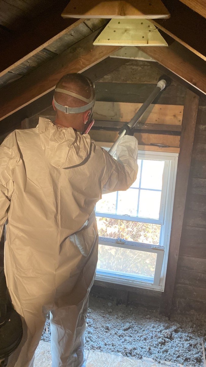 Abate Pro technician in protective equipment removing attic mold